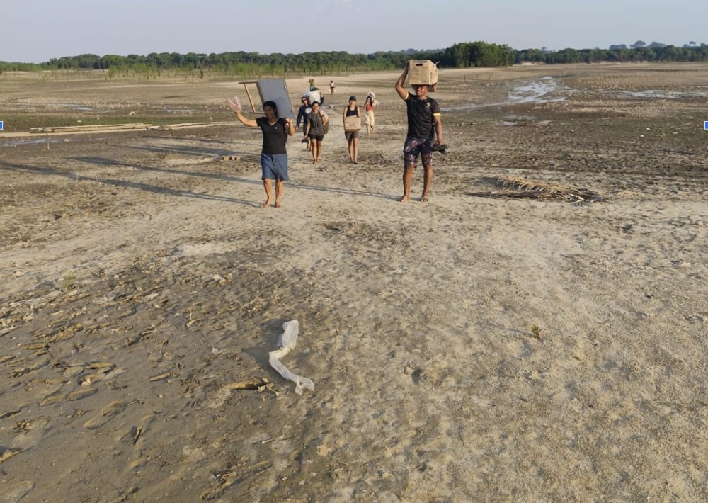 Quilombola community members carrying water, walking through what usually is the bottom of Lake Tefé. Photo taken on Sept 07 2024. Photo courtesy of IIEB